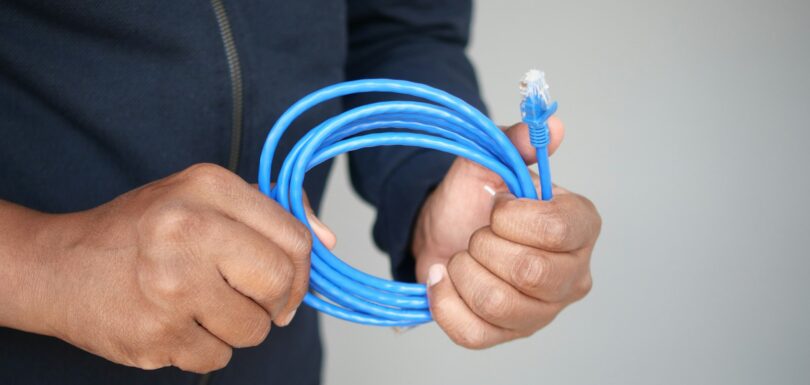 A closeup of hands holding a coiled blue Ethernet cable for a network connection